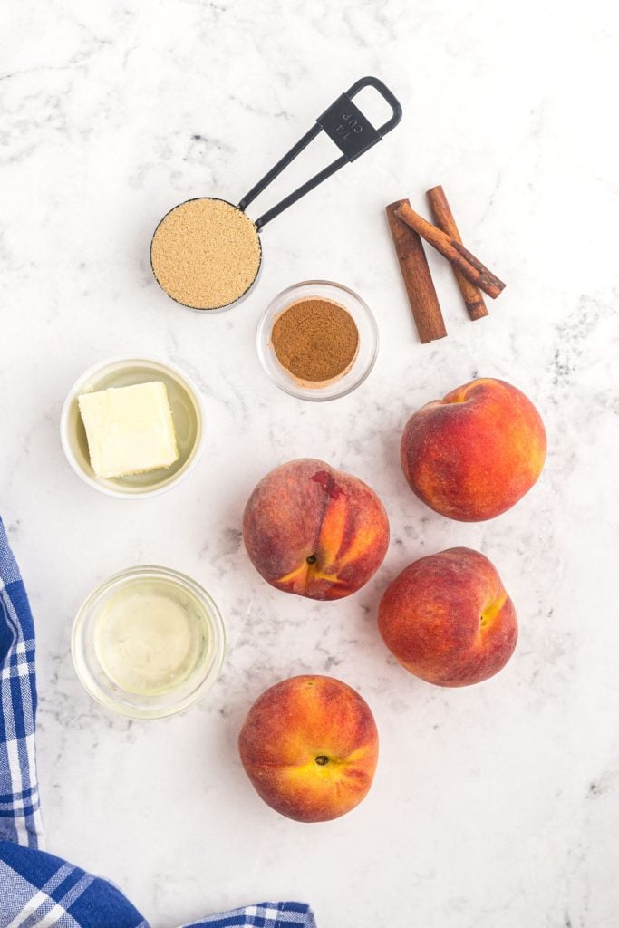 Ingredients needed to make air fryer peaches on a white marble table