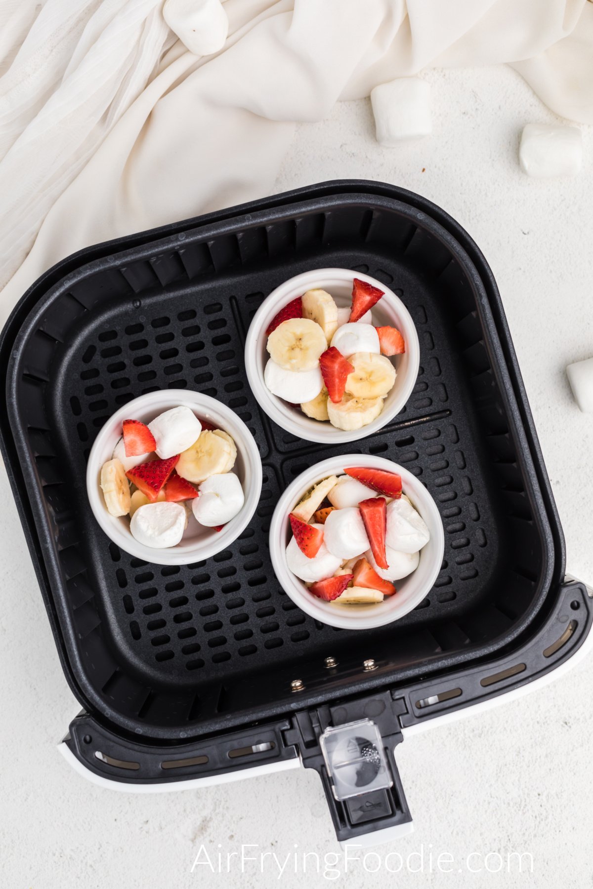 Air fryer strawberry banana bowls in the basket of the air fryer ready to cook.