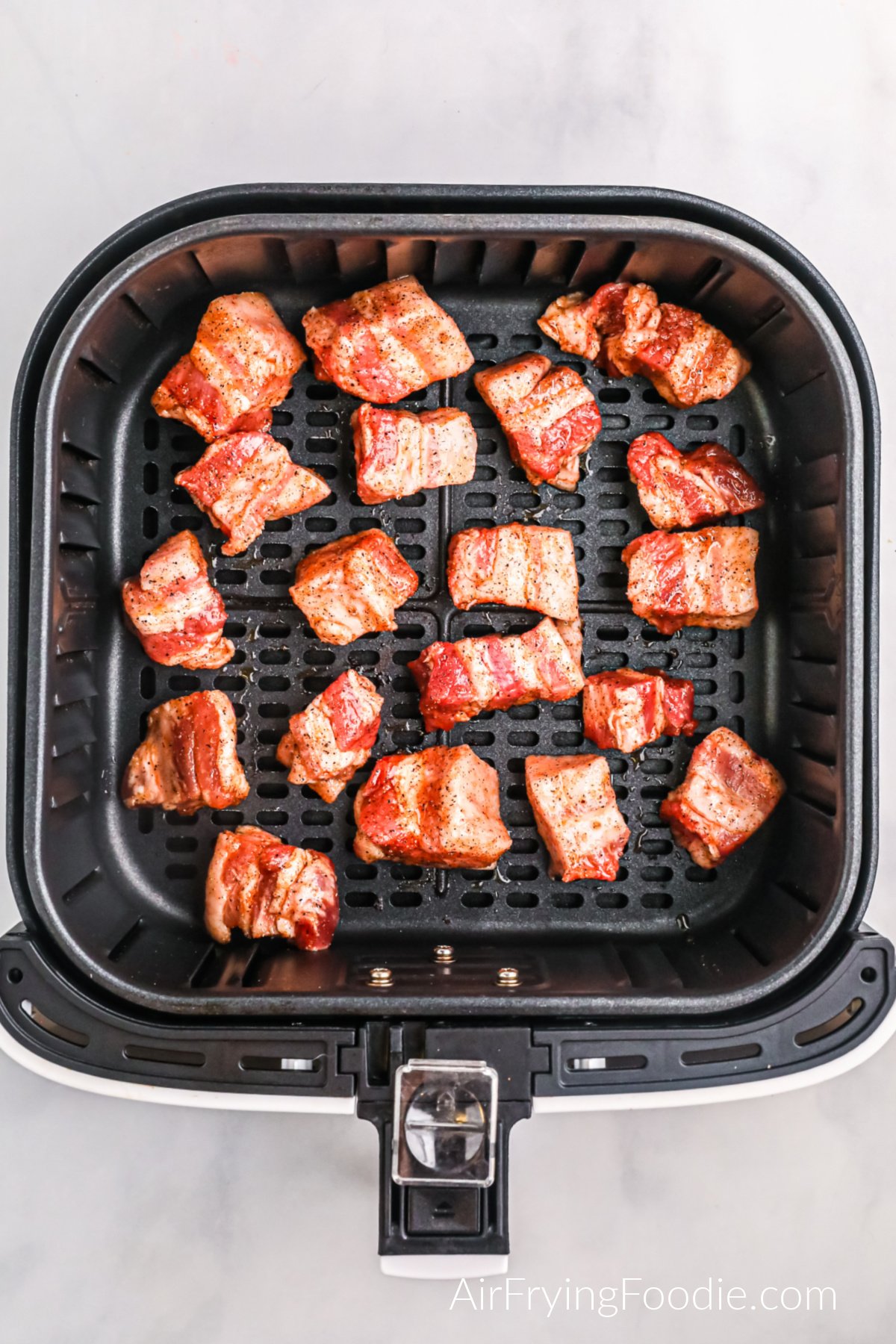 Pork belly bites in the basket of the air fryer, ready to cook.