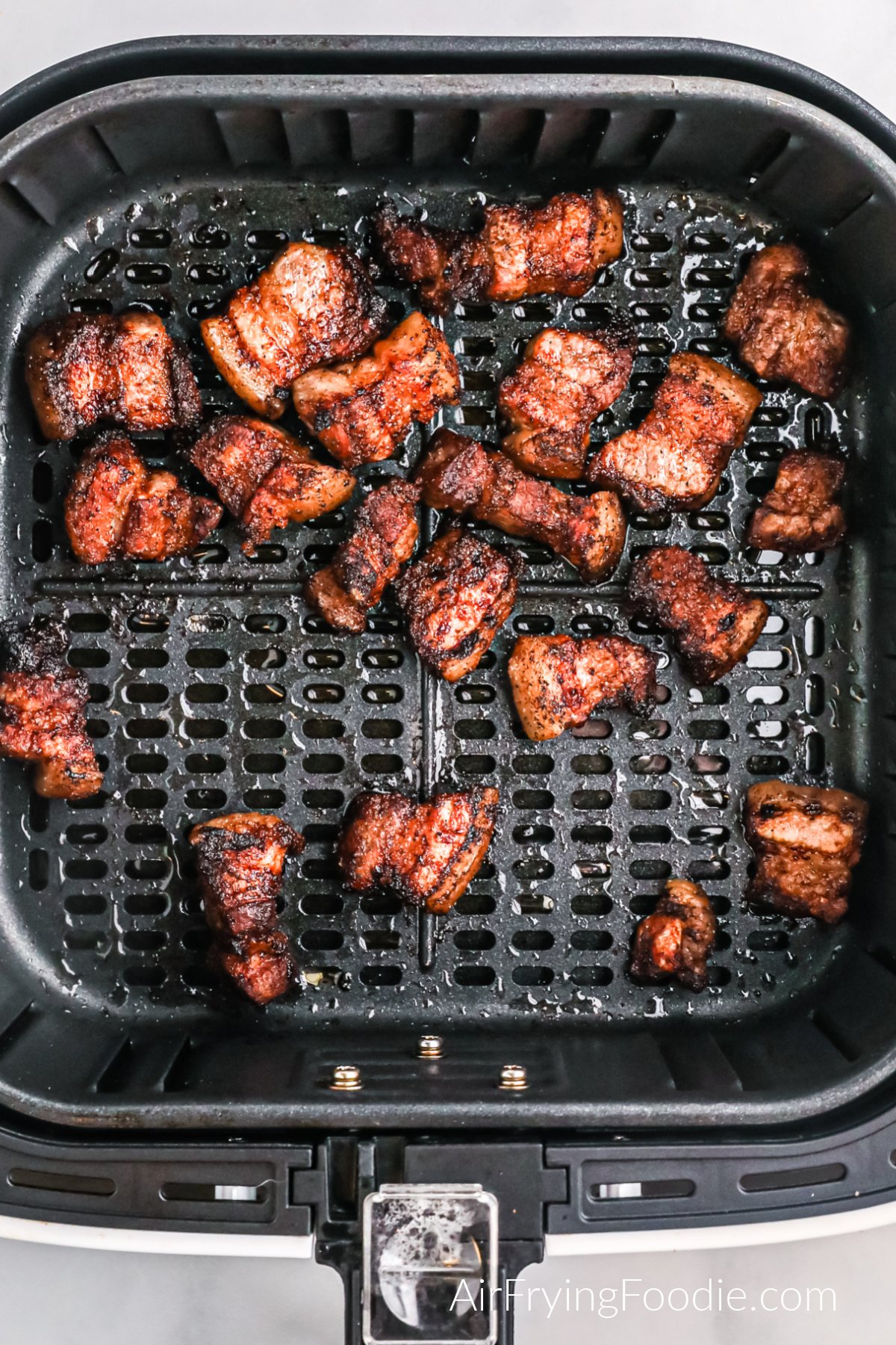 Fried pork belly bites in the basket of the air fryer.