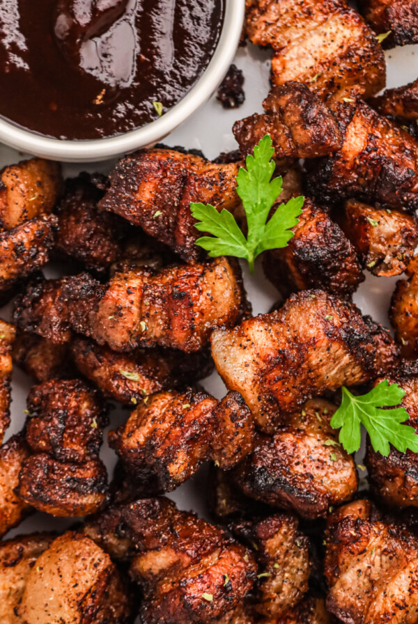 Overhead photo of crispy air fryer pork belly bites in a serving platter with BBQ dipping sauce.