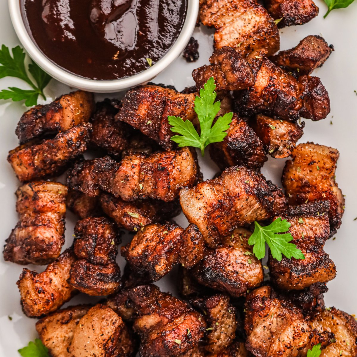 Overhead photo of crispy air fryer pork belly bites in a serving platter with BBQ dipping sauce.