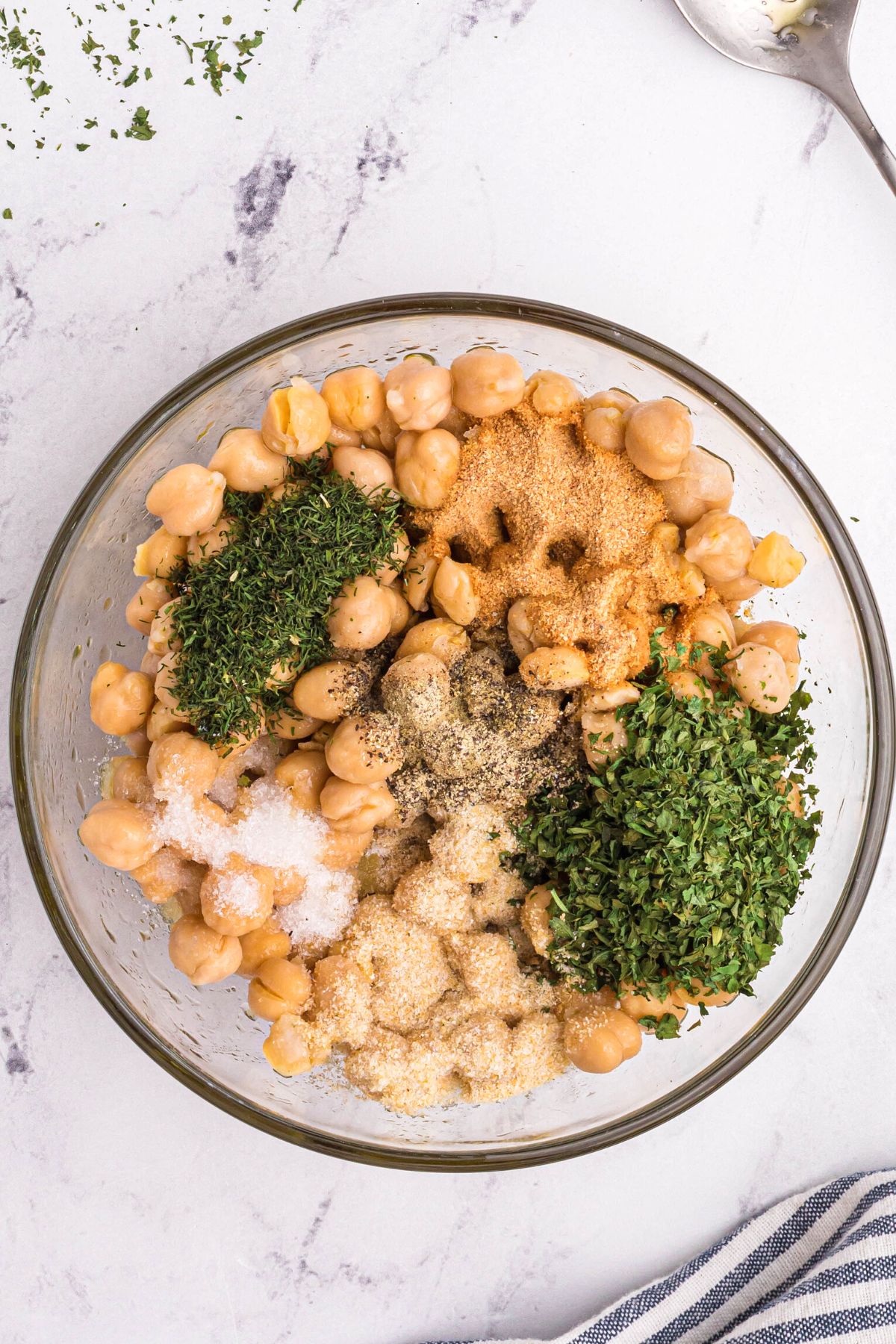 Chickpeas mixed with seasonings in a clear glass bowl