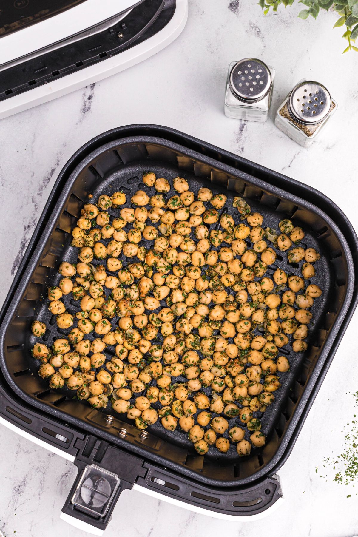 Coated chickpeas in the air fryer basket before being cooked