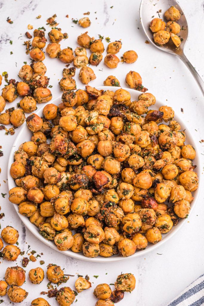golden brown crispy chickpeas after being cooked in the air fryer basket on a white marble table with a serving spoon
