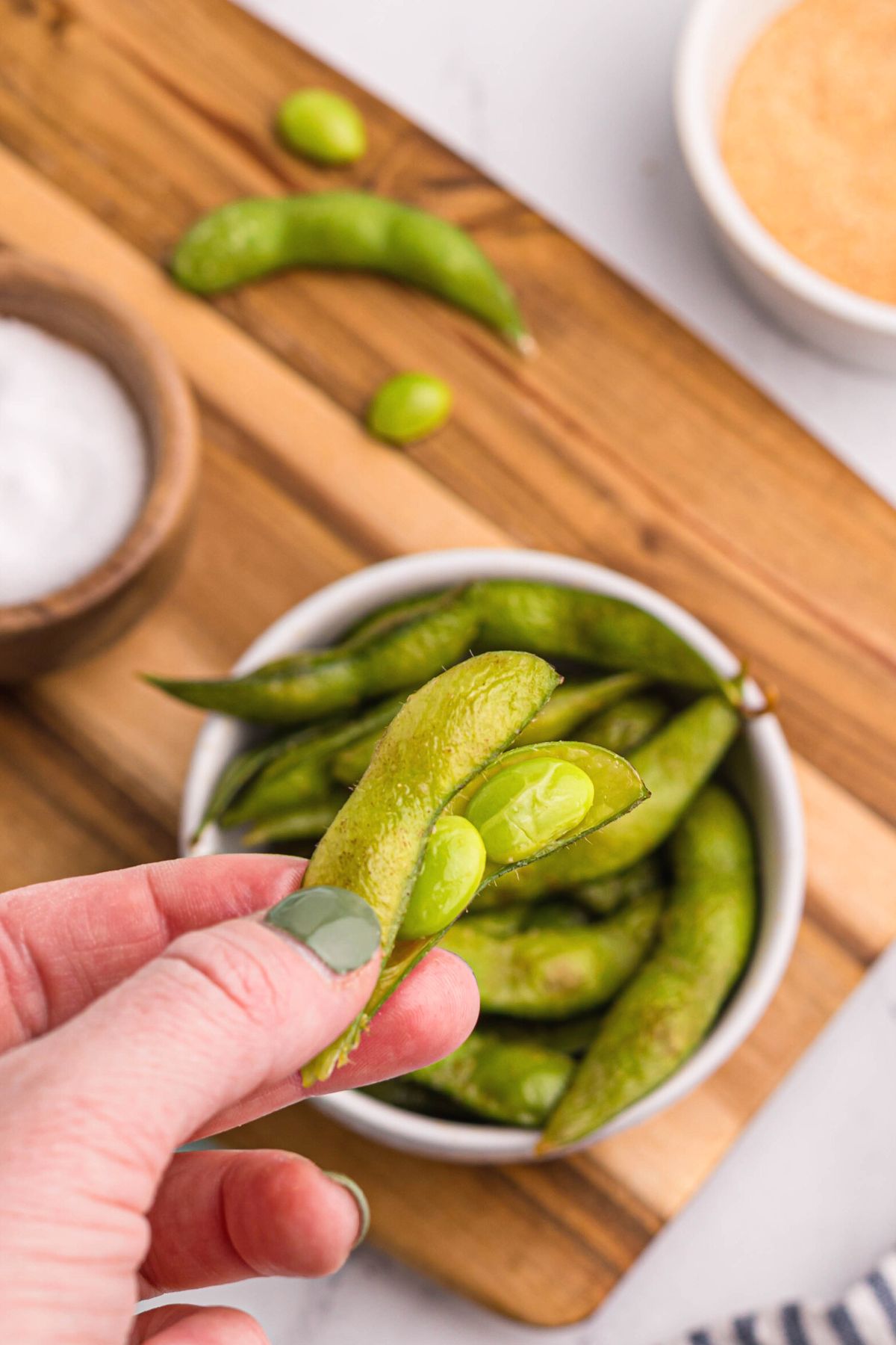Edamame pods with seeds being removed after being cooked in the air fryer