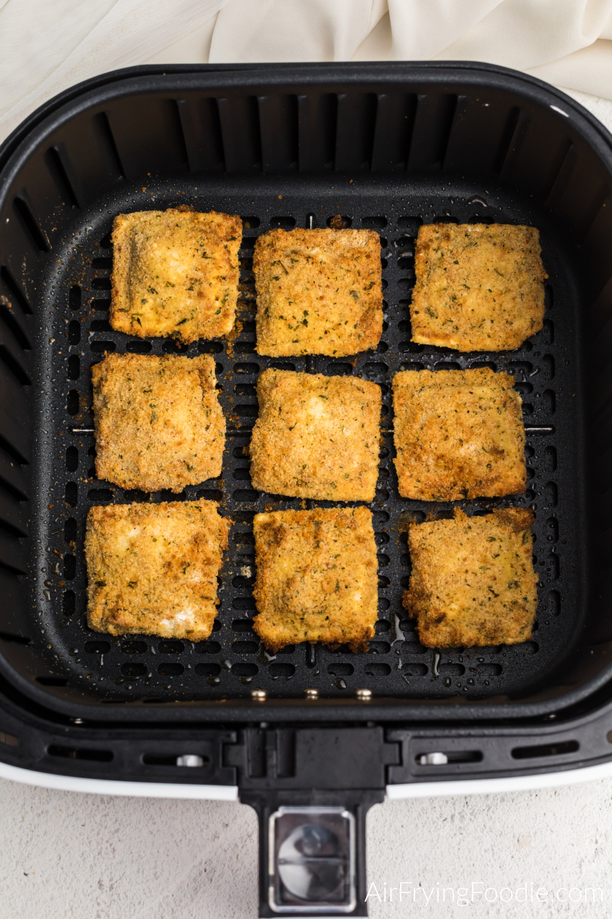 Fully cooked fried Ravioli in the basket of the air fryer. 