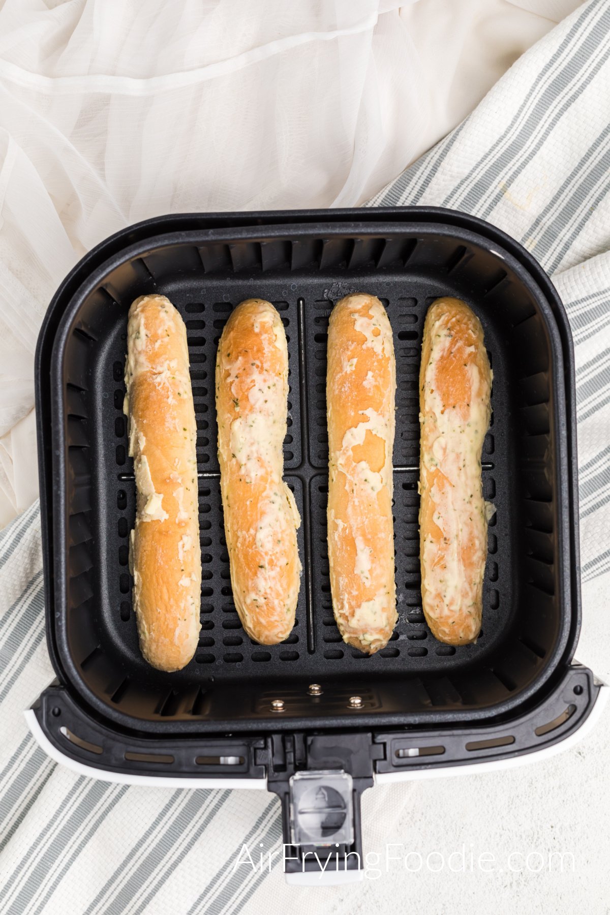 Frozen breadsticks in the basket of the air fryer. 