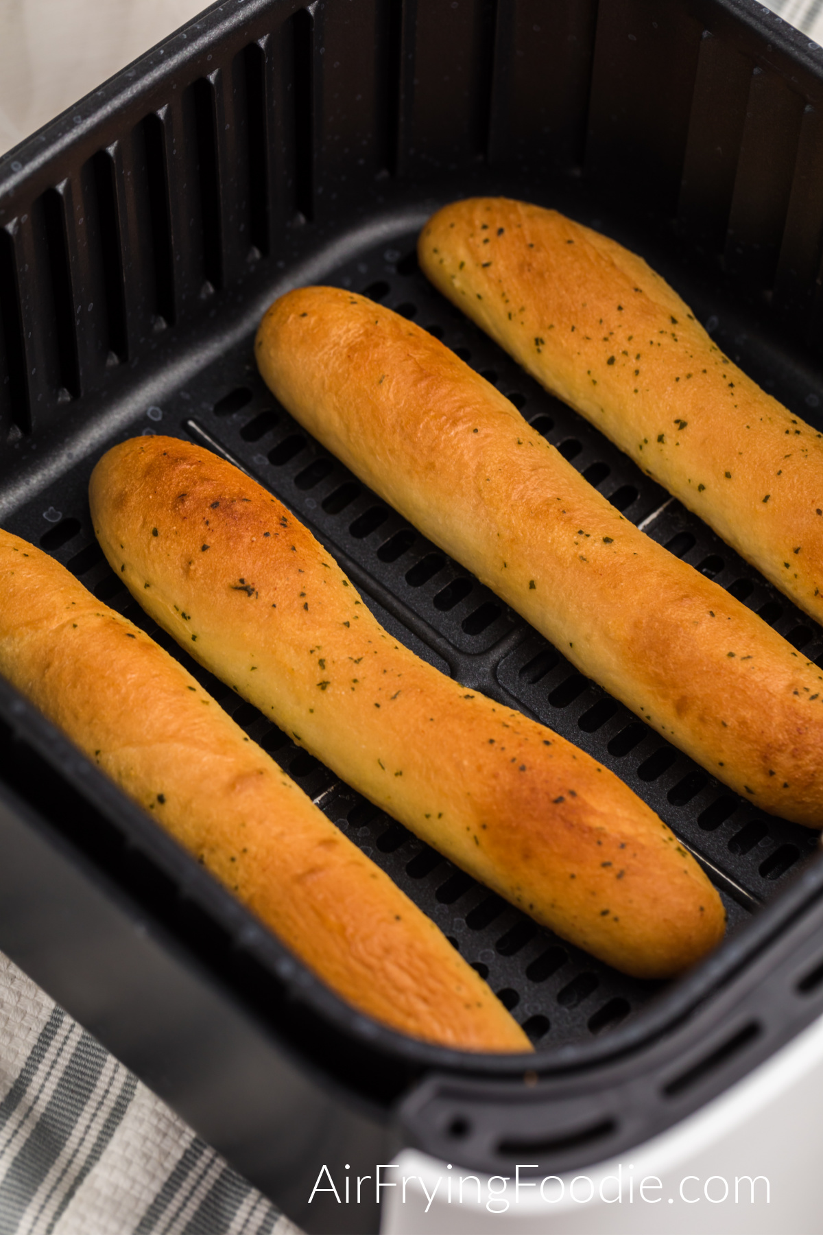 Fully cooked breadsticks in the basket of the air fryer, ready to be removed and served. 