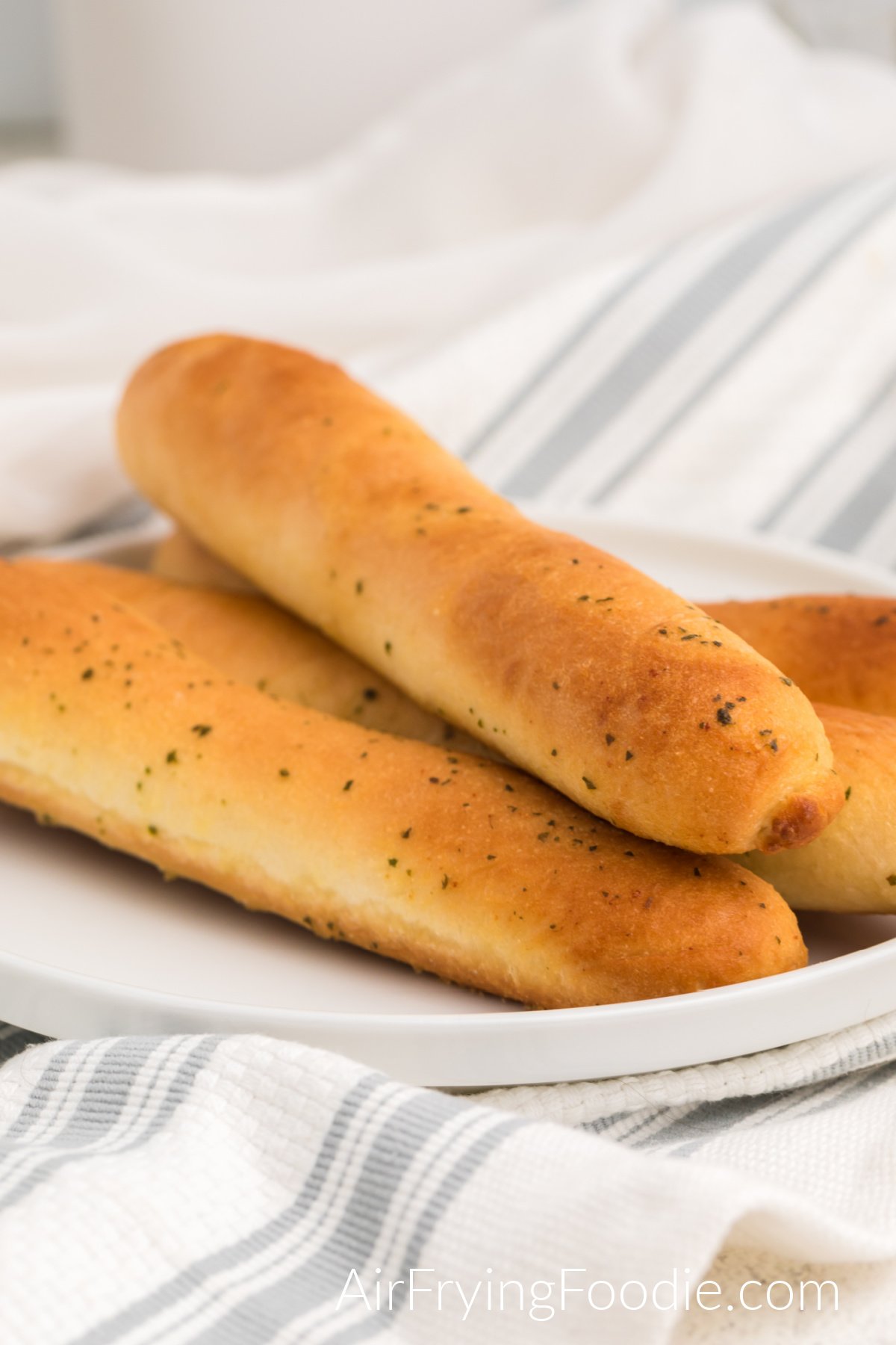 Fully cooked breadsticks stacked on a plate, ready to serve.