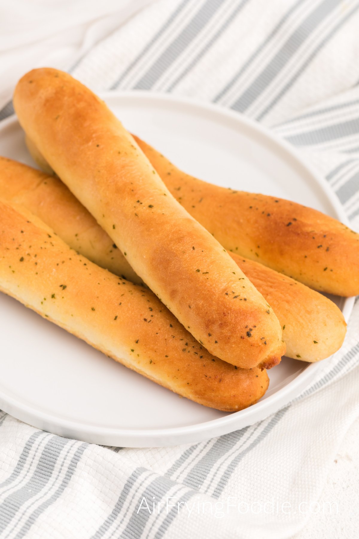 Breadsticks made in the air fryer and served on a white plate. 