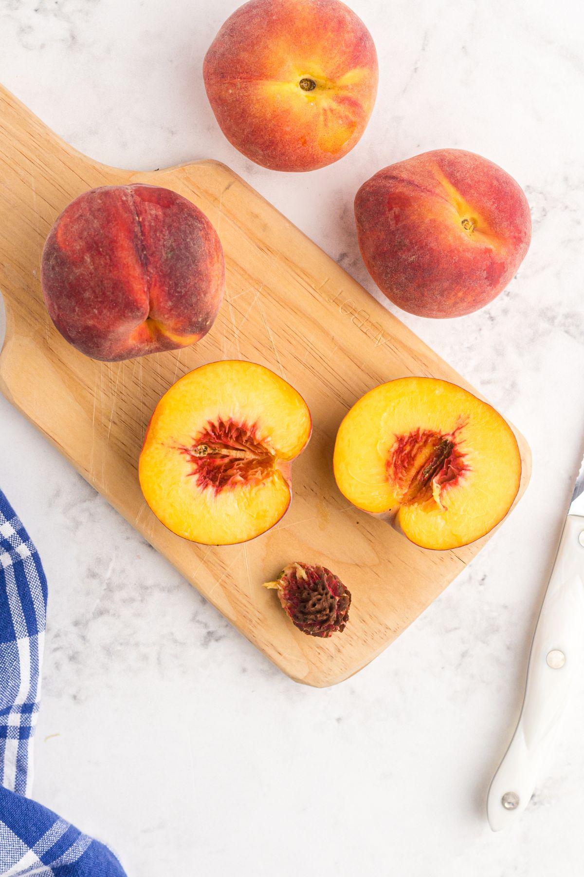Golden yellow peaches sliced in half on a cutting board with pits removed