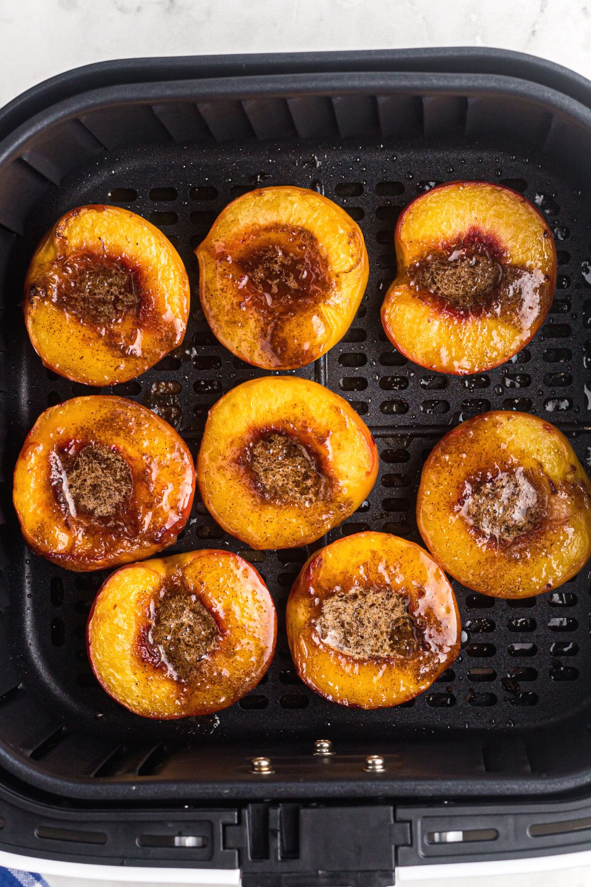 Juicy golden peaches with melted butter and sugar on top after being cooked in the air fryer basket