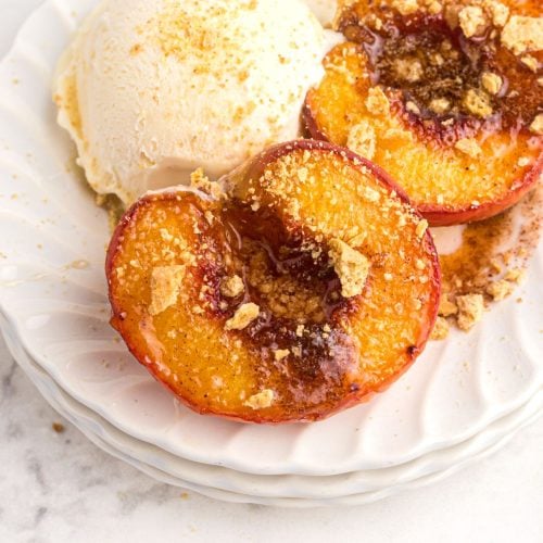 Golden juicy peaches on a white plate and served with vanilla ice cream