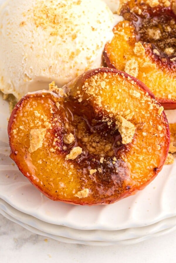 Golden juicy peaches on a white plate and served with vanilla ice cream