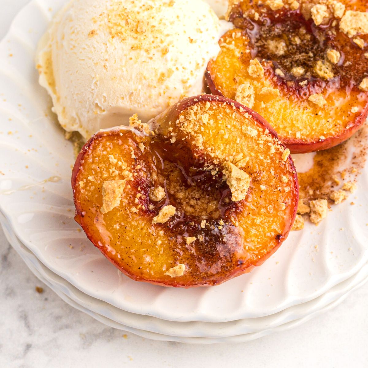 Golden juicy peaches on a white plate and served with vanilla ice cream