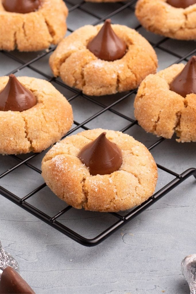 Golden brown peanut butter cookie topped with chocolate kiss candy on a cooling rack
