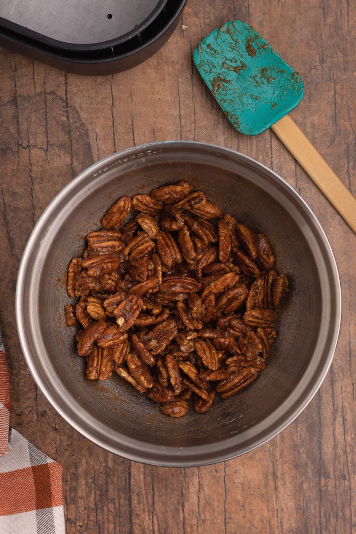 All ingredients mixed together coating pecans in a bowl before being put in the air fryer basket