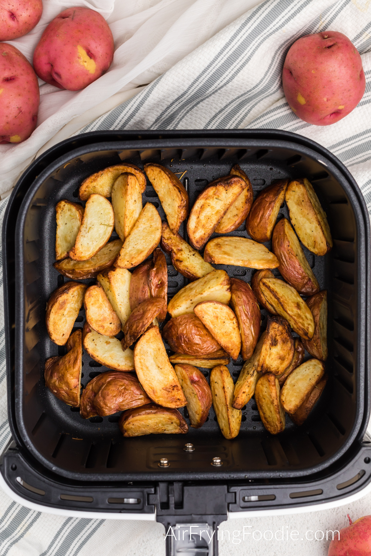 Seasoned golden brown red potatoes in the basket of the air fryer.