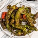 Overhead picture of air fried shishito peppers on a white plate.