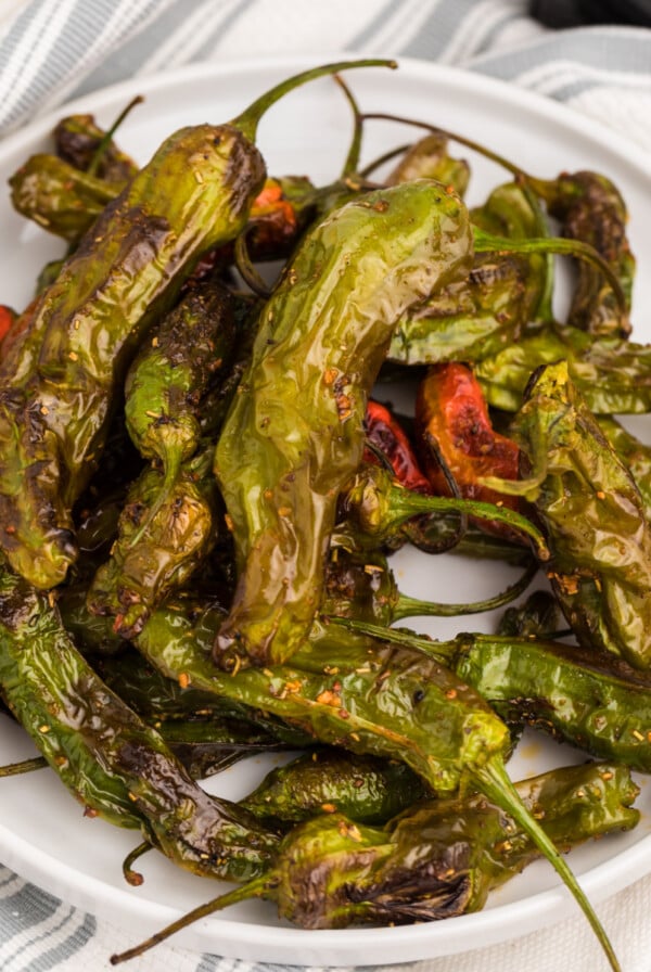 Overhead picture of air fried shishito peppers on a white plate.