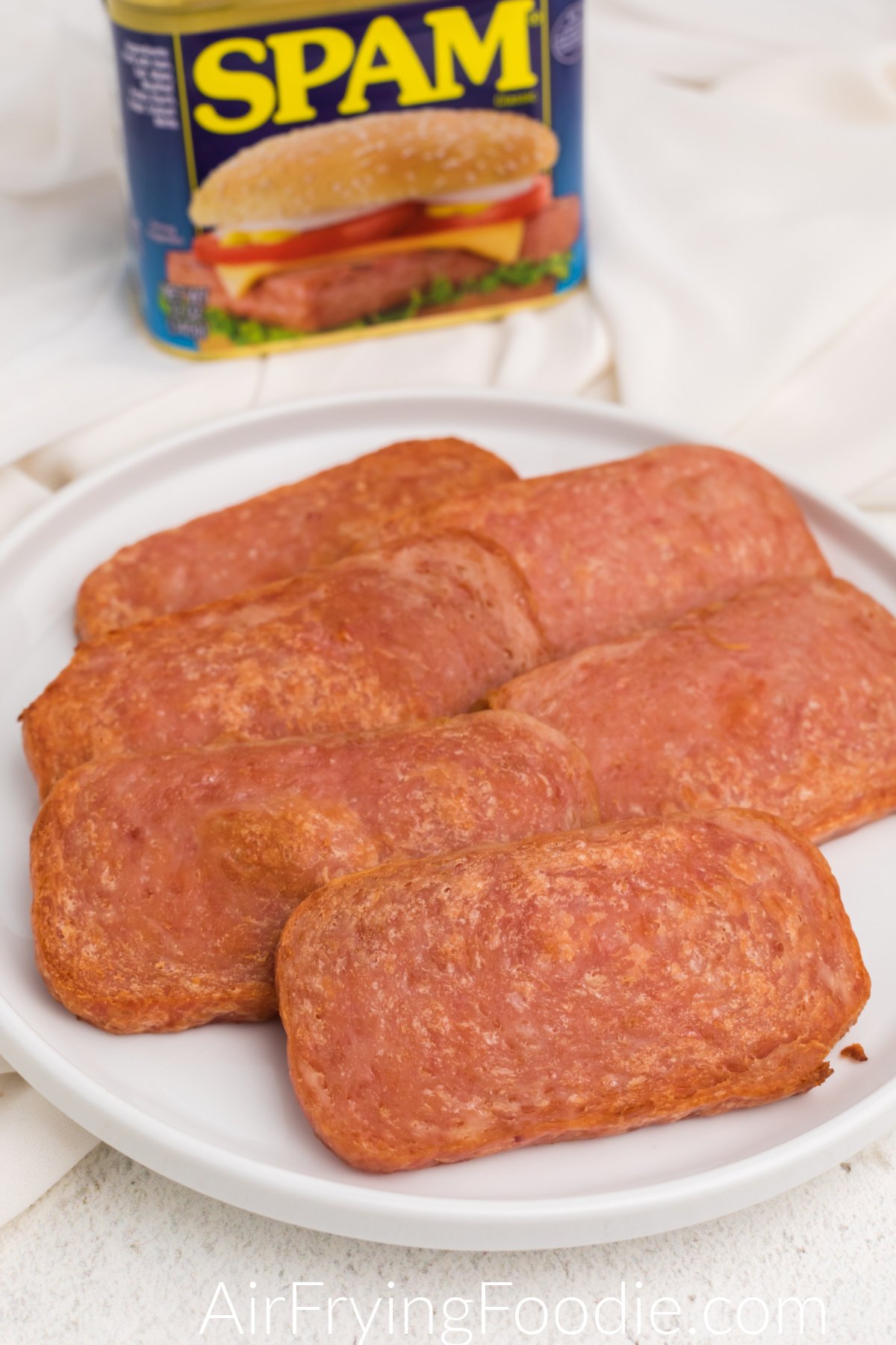 Slices of cooked Spam made in the air fryer and served on a white plate. 