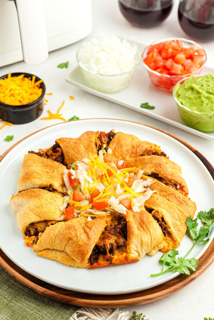 golden flaky crusted crescents filled with taco  meat in the shape of a circle on a white plate with taco seasonings measured out on the table