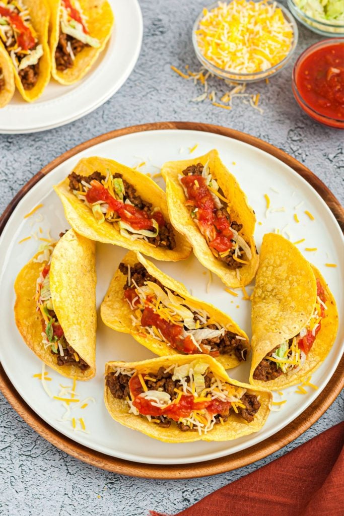 
crispy taco shells filled with taco fillings on a white plate