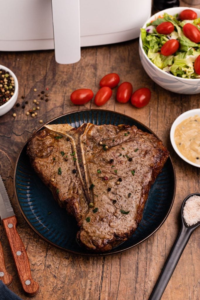 Juicy tbone steak on a blue plate served on a wooden table