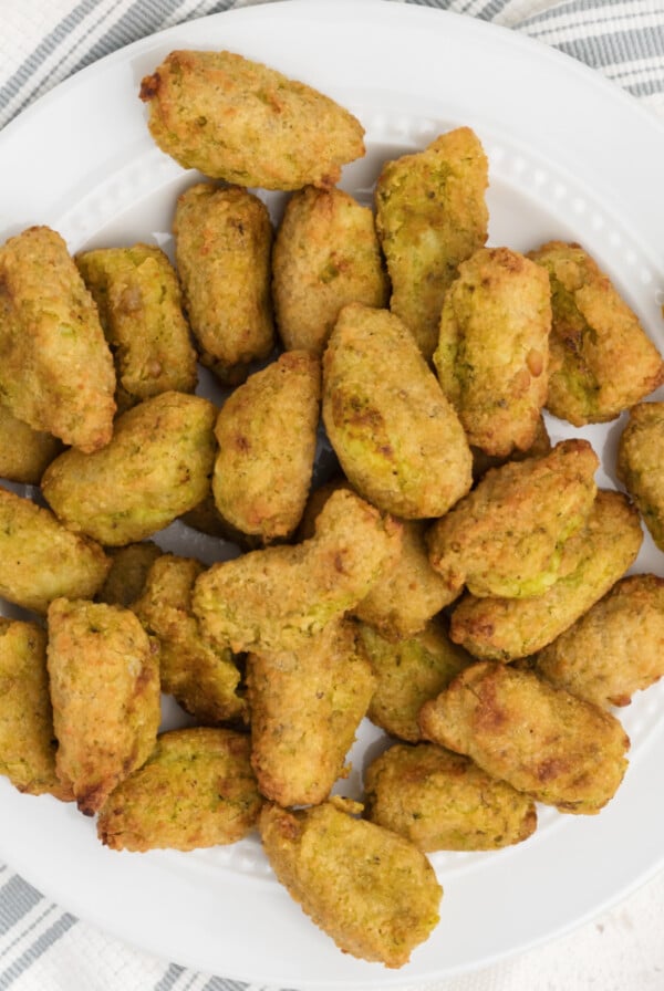 Overhead photo of broccoli and cheese veggie tots on a white plate, ready to serve.