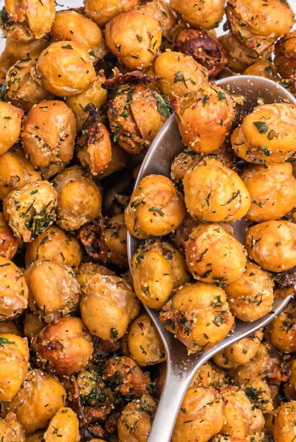 Golden crispy brown chickpeas in a white bowl with a serving spoon