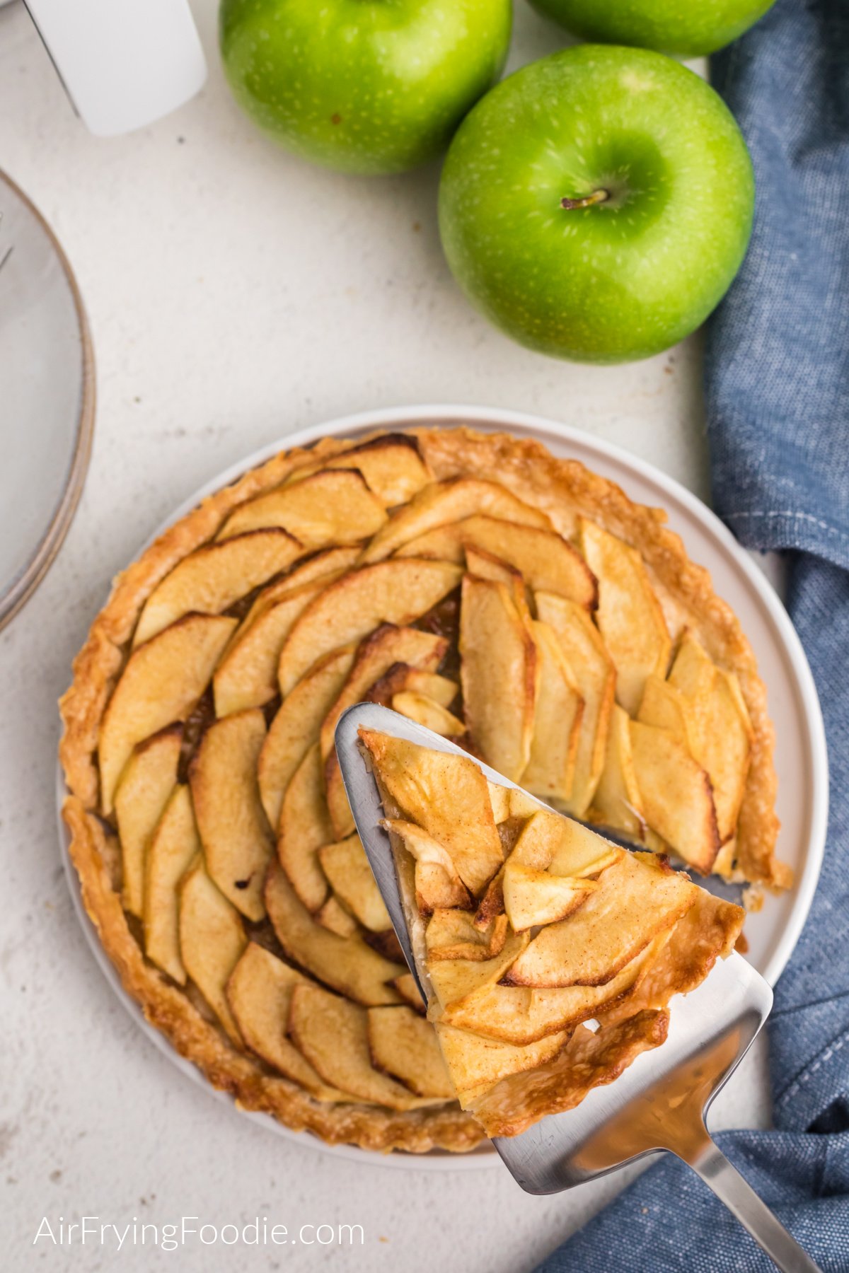 Apple tart on a plate with a slice cut out of it.