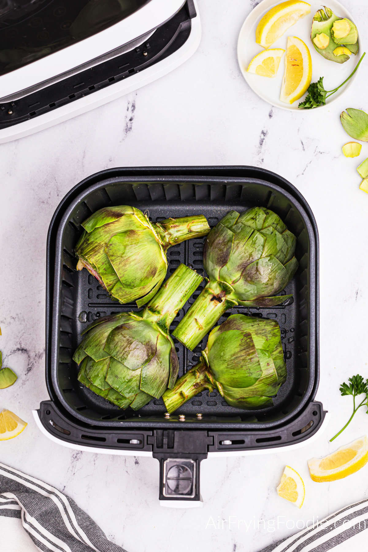 Artichoke halves placed face side down into the basket of the air fryer. Ready to cook.