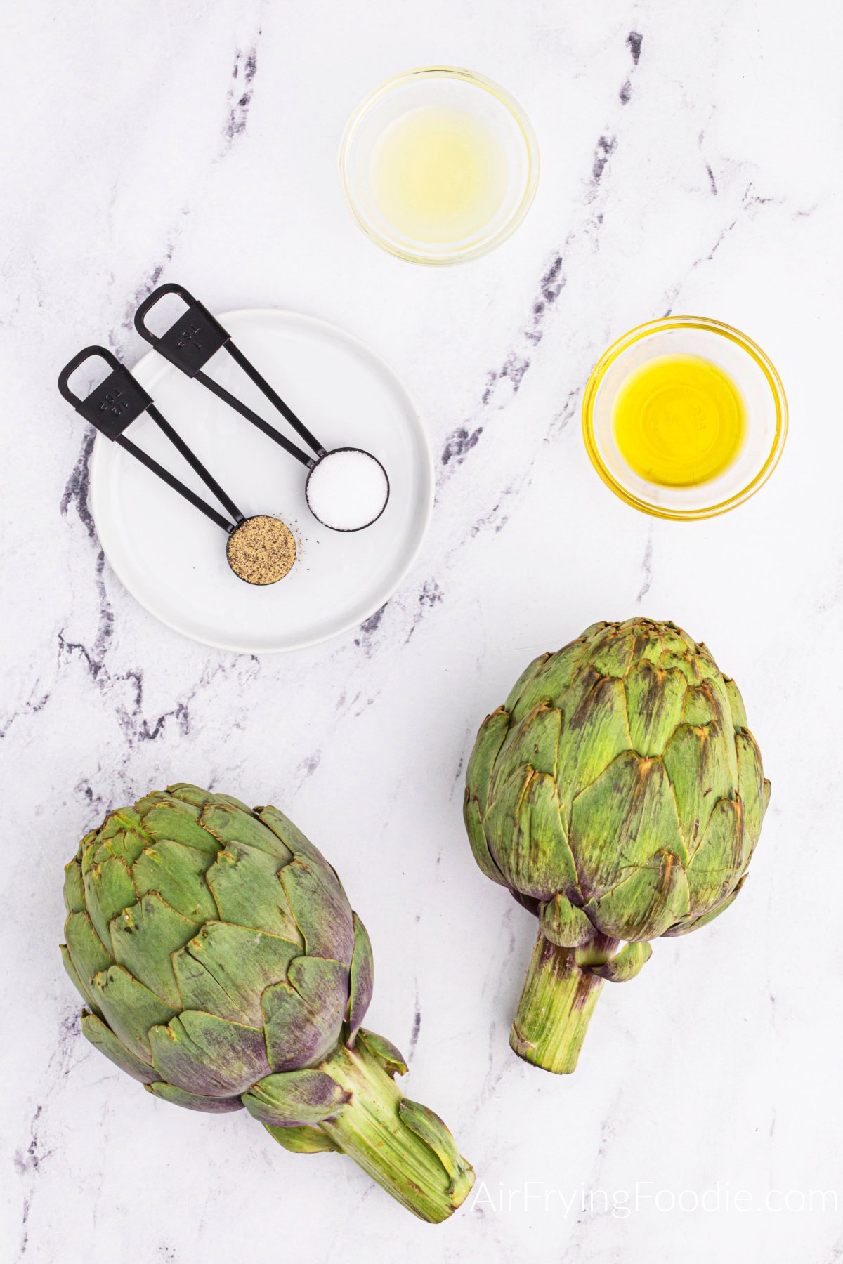 Ingredients needed for air fryer artichoke on a white table top. 