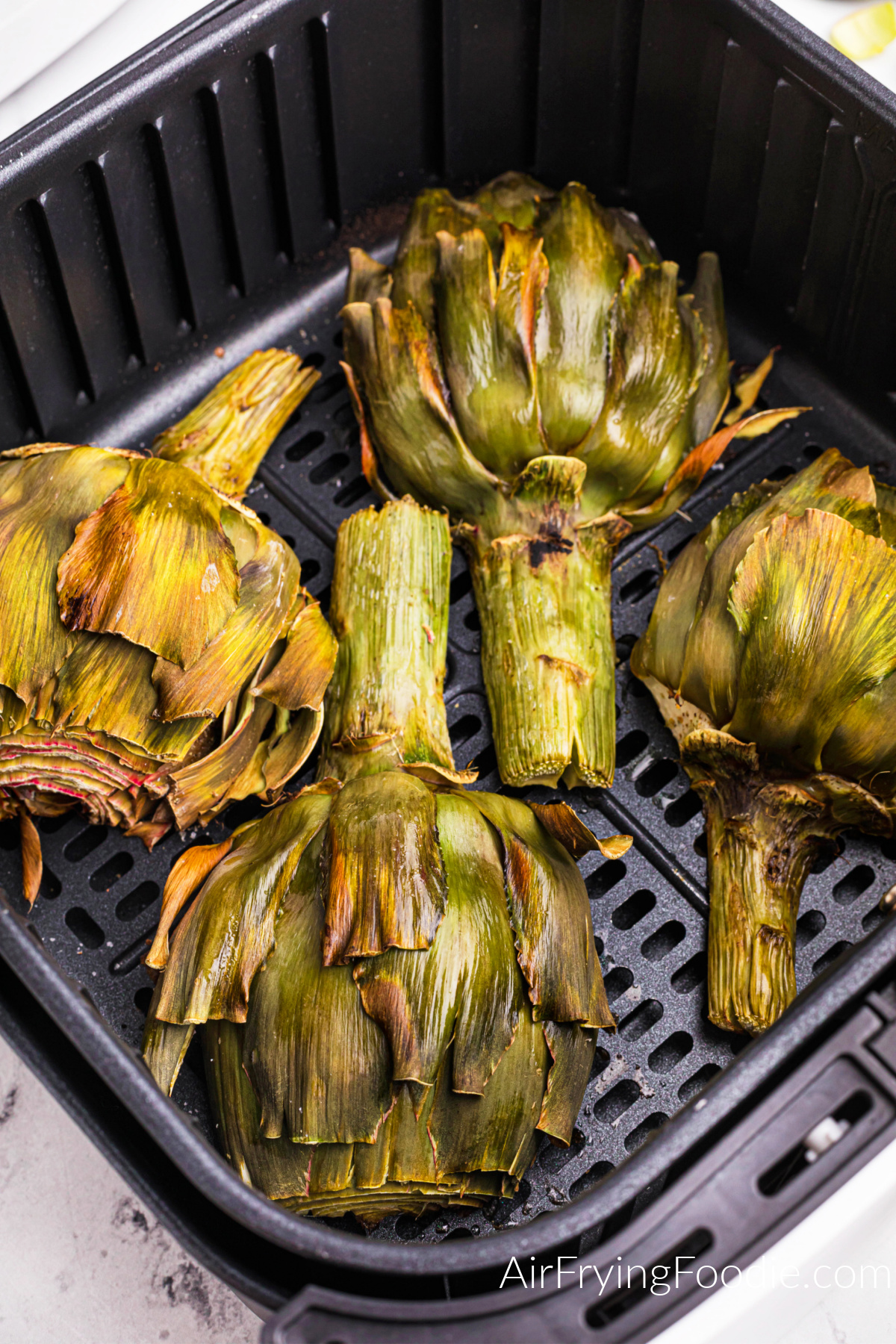 Cooked artichoke in the basket of the air fryer.