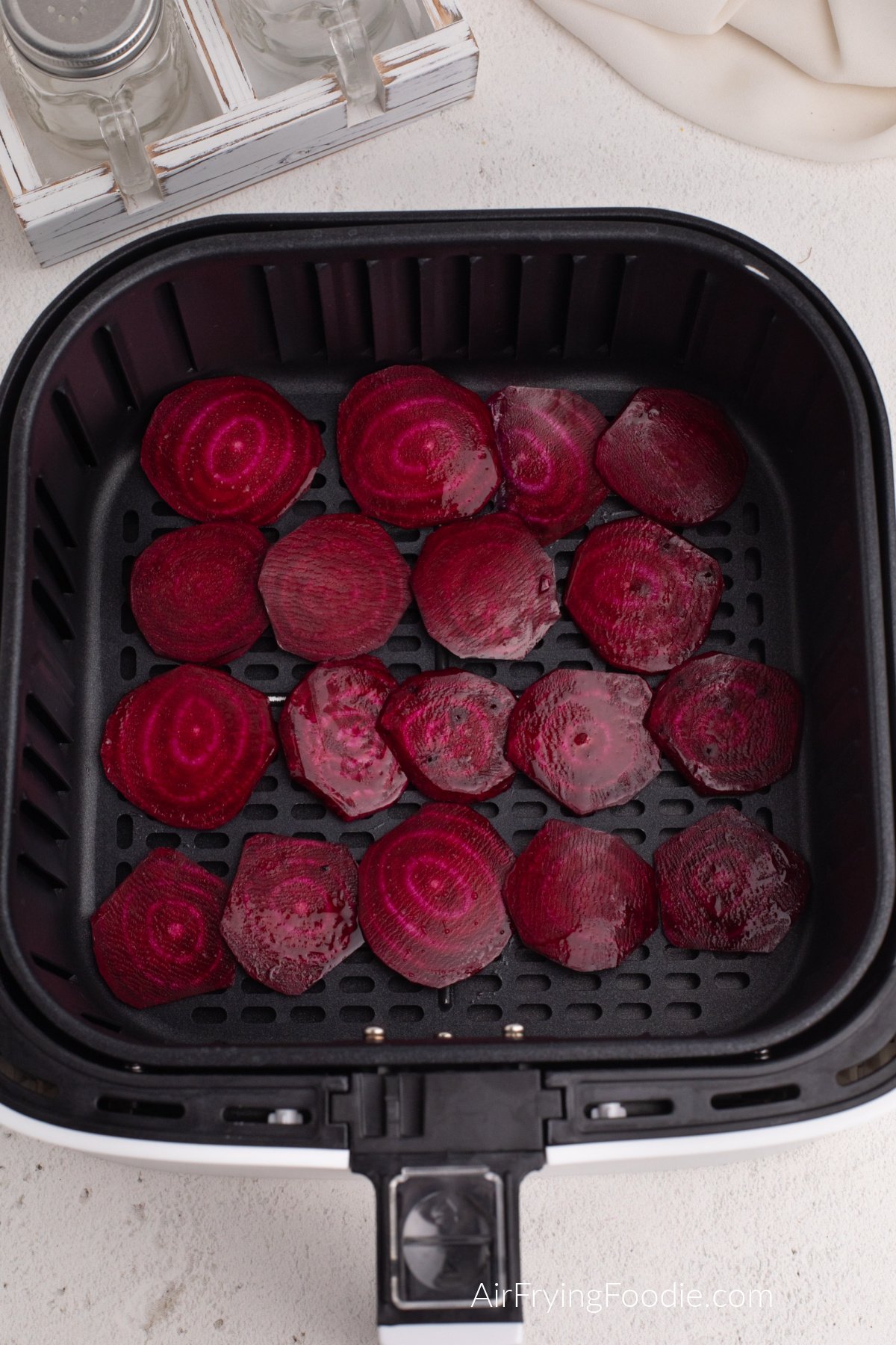 Sliced beets placed in a single layer in the basket of the air fryer.