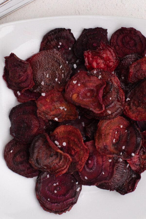 Overhead shot pf beet chips made in the air fryer, served on a whote plate, and topped with kosher salt.