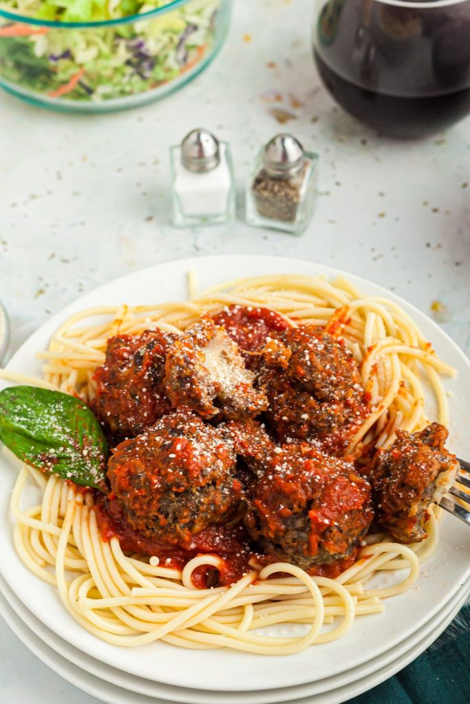 Air Fryer Cheese Stuffed Meatballs served over pasta on a marble table.