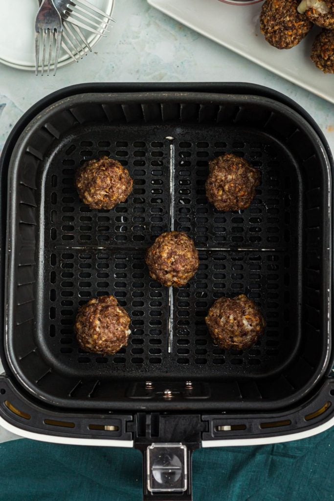 Cooked meatballs in the air fryer basket.