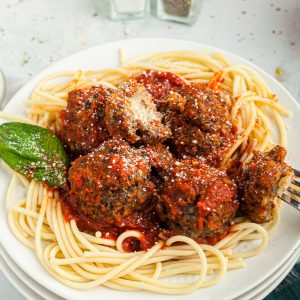 Cheese stuffed meatballs served over pasta on a white plate