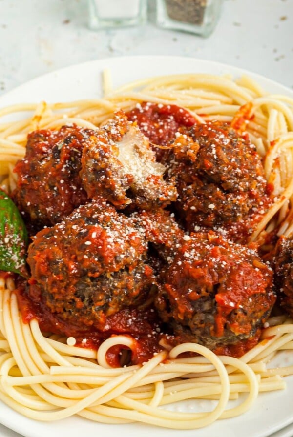 Cheese stuffed meatballs served over pasta on a white plate