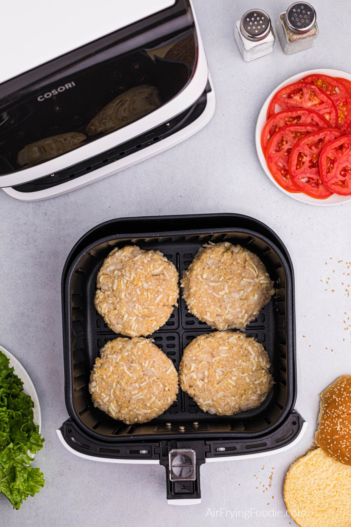 Chicken burger patties in a single layer in the basket of the air fryer.
