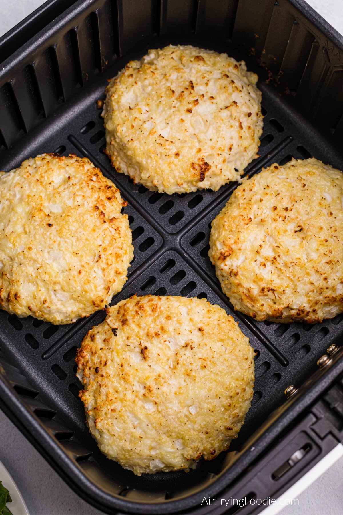 Chicken burgers that have been air fried in the basket of the air fryer.
