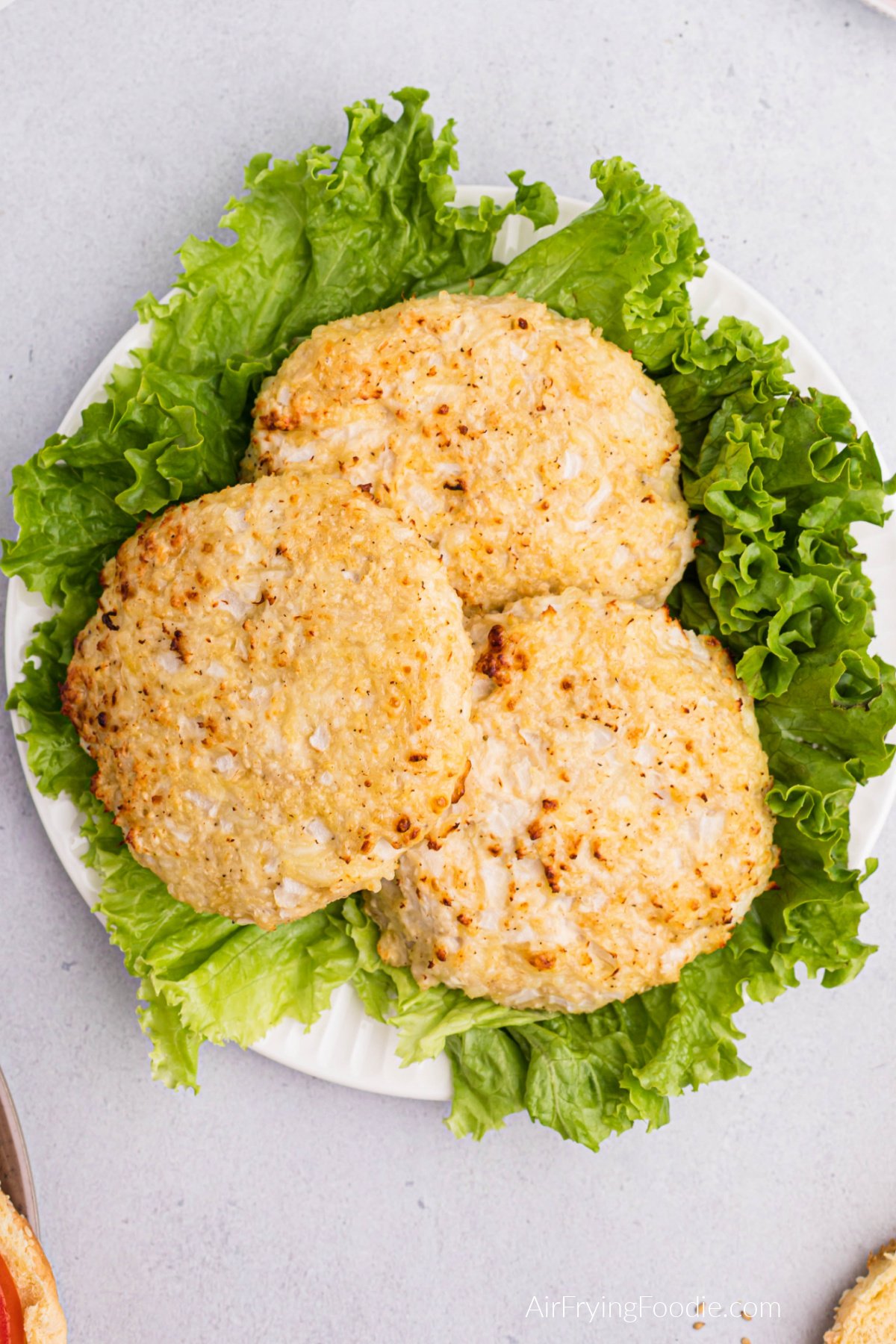 Chicken burgers stacked on a plate with lettuce, ready to be served.