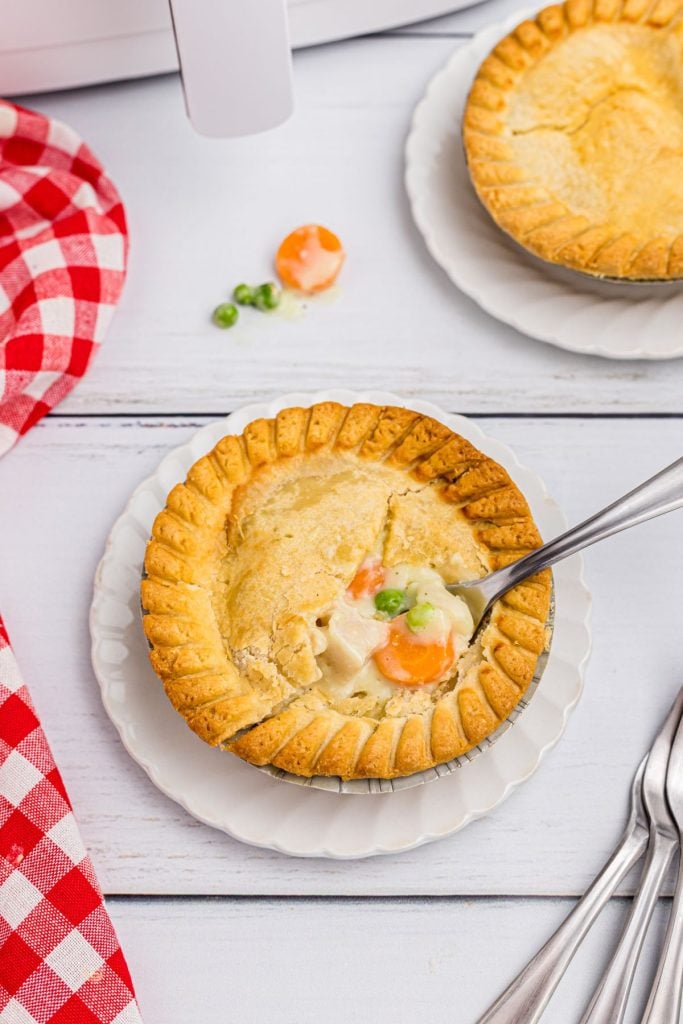 Golden pot pie on a white plate with a fork in the center of the pie