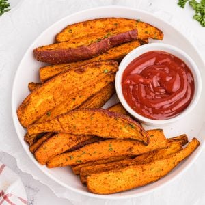 Overhead photo of sweet potato wedges made in the air fryer and served with a side of ketchup.