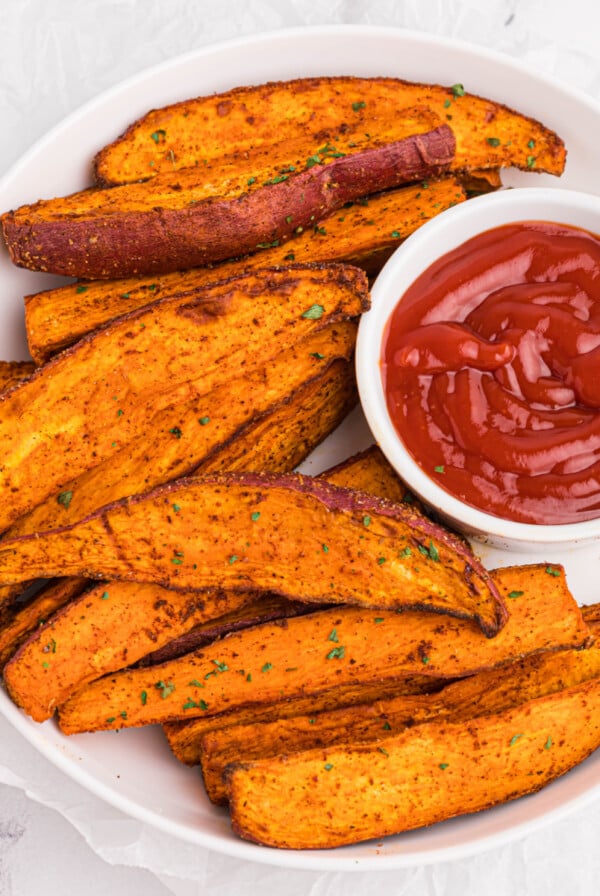 Overhead photo of sweet potato wedges made in the air fryer and served with a side of ketchup.