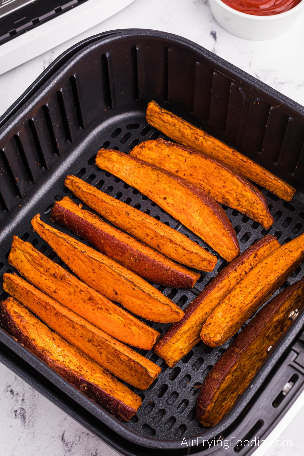 Fully cooked and air fried sweet potato wedges in the air fryer basket.