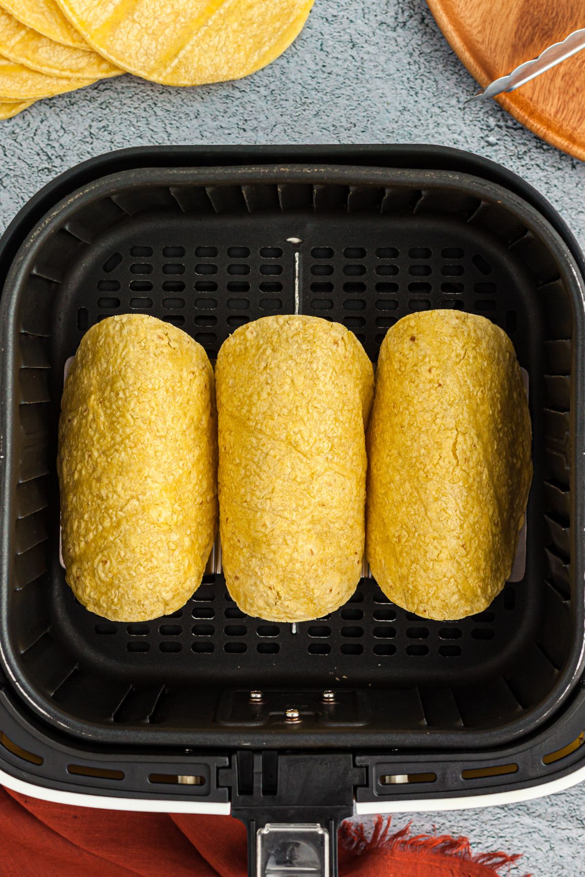 Tortillas draped over a mold in the air fryer basket
