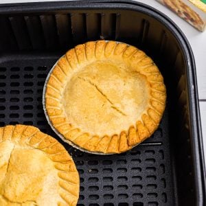 Golden pot pies in an air fryer basket after being cooked